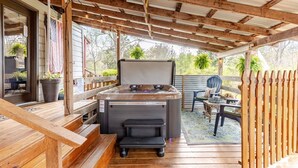 An outdoor patio with a hot tub, wooden deck, and a covered seating area. - Guest Cottage,Dog friendly, minutes to Clayton, fenced yard, hot tub on patio. (Tiger)