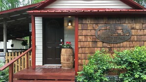 A wooden building with a porch, a door, and a sign that reads "Every Farm Has a Story." - Guest Cottage,Dog friendly, minutes to Clayton, fenced yard, hot tub on patio. (Tiger)