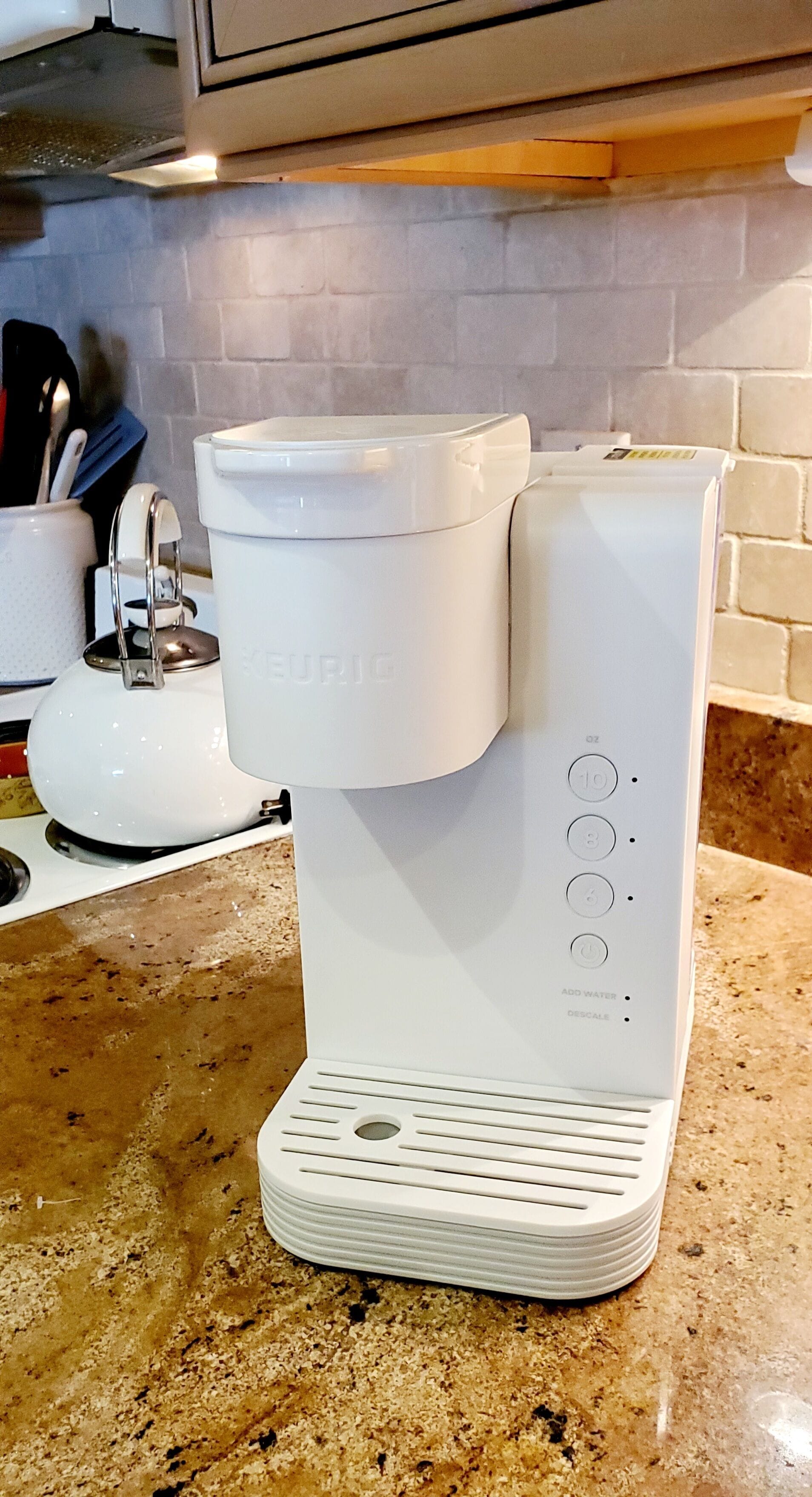 A white coffee maker with a digital display and control buttons on a kitchen counter.
