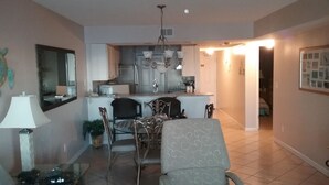 A compact living space with a dining area, kitchen, and a hallway leading to another room. - Beachfront in the heart of Gulf Shores (Gulf Shores)