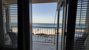 A view from a balcony to a beach with a metal railing and a door leading to the balcony. - Beachfront in the heart of Gulf Shores (Gulf Shores)