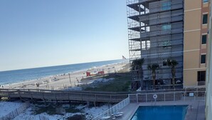 A deck with a pool, lounge chairs, and a view of the beach. - Beachfront in the heart of Gulf Shores (Gulf Shores)