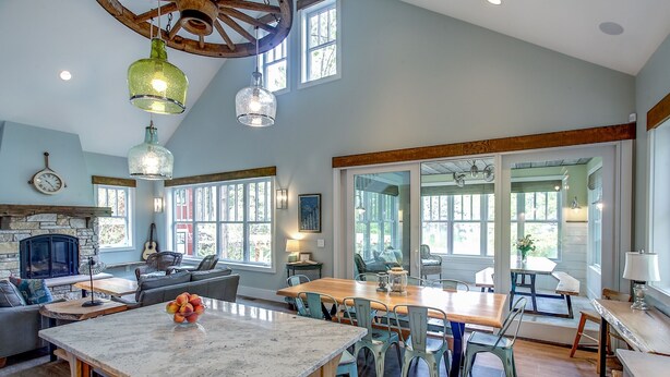 A spacious kitchen with a central island, large windows, and a rustic ceiling. - Newly Built Luxury Lakefront Cottage with Fire Pit, Dock, Game Room (Traverse City)