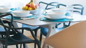 A dining table set with bowls, plates, and glasses, surrounded by chairs. - Spacious Ocean Oasis with Private Outdoor Shower! (Encinitas)