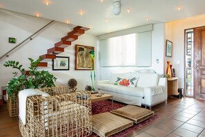 Een moderne woonkamer met een witte bank, een houten trap en een groot raam.