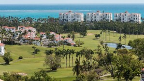 Un resort con varias edificaciones, un campo de golf y vista al océano.