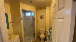 Un baño pequeño con ducha, inodoro y lavabo.