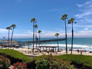 A beach with a pier, palm trees, and a boardwalk.