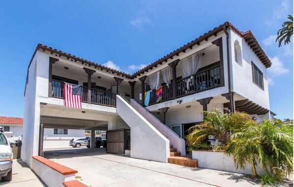 A two-story building with a covered parking area, a staircase, and a balcony with an American flag. - Beach Studio San Clemente Orange County California (San Clemente)