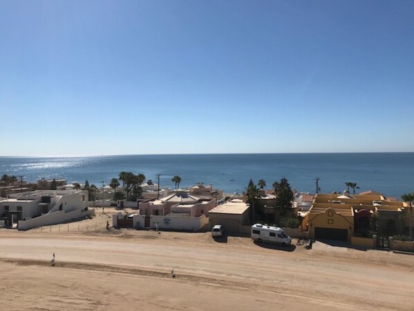 Una zona costera con edificios, una playa de arena y el mar al fondo.