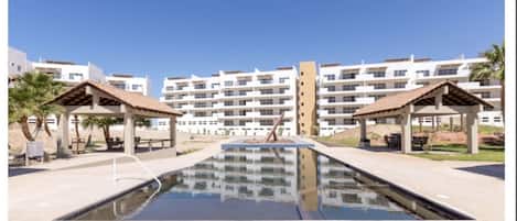 A swimming pool with two gazebos, surrounded by multi-story buildings with balconies.