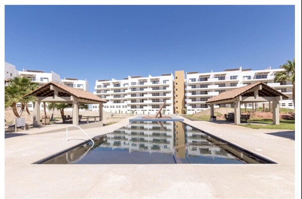 A swimming pool with two gazebos, surrounded by multi-story buildings with balconies.