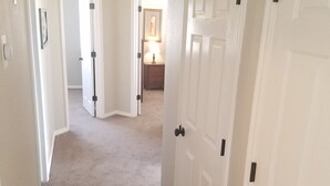 Un pasillo con pisos alfombrados que conduce a un dormitorio con una puerta.