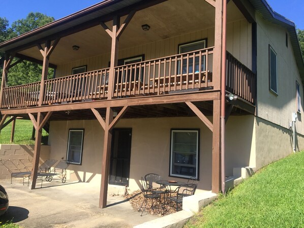 A two-story building with a balcony, outdoor seating, and a stone wall.