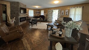 Una sala de estar acogedora con chimenea de piedra, paredes de madera y un espacio de descanso confortable.