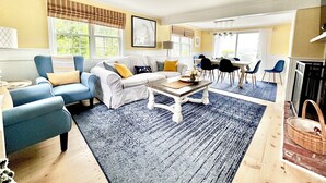 Ein Wohnzimmer mit einer Couch, Sesseln, einem Couchtisch und einem Essbereich mit Stühlen und Tisch.