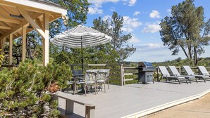 A wooden deck with outdoor seating, a grill, and a large umbrella. - A Great Home in a Resort-Like Setting--
Private Retreat with pool & River Views (Valley Springs)