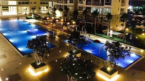 Ein Hotel mit mehreren Etagen und einem Poolbereich auf dem Dach, inklusive zwei Schwimmbecken und einer Lounge mit Sitzgelegenheiten.