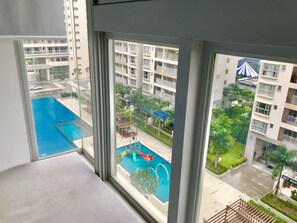 Blick aus einem Fenster eines Wohnhauses auf einen Poolbereich mit Rutsche und Zelt.