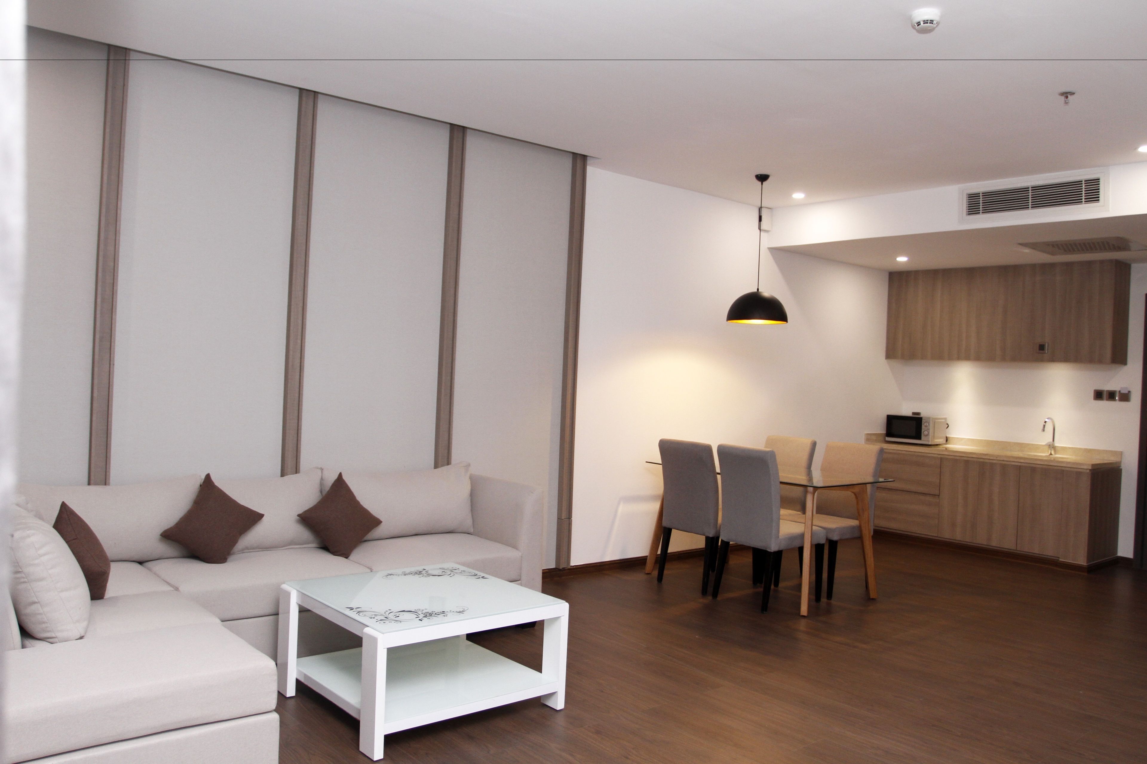 Un salon moderne comprenant un canapé, une table basse et un coin repas avec des chaises.