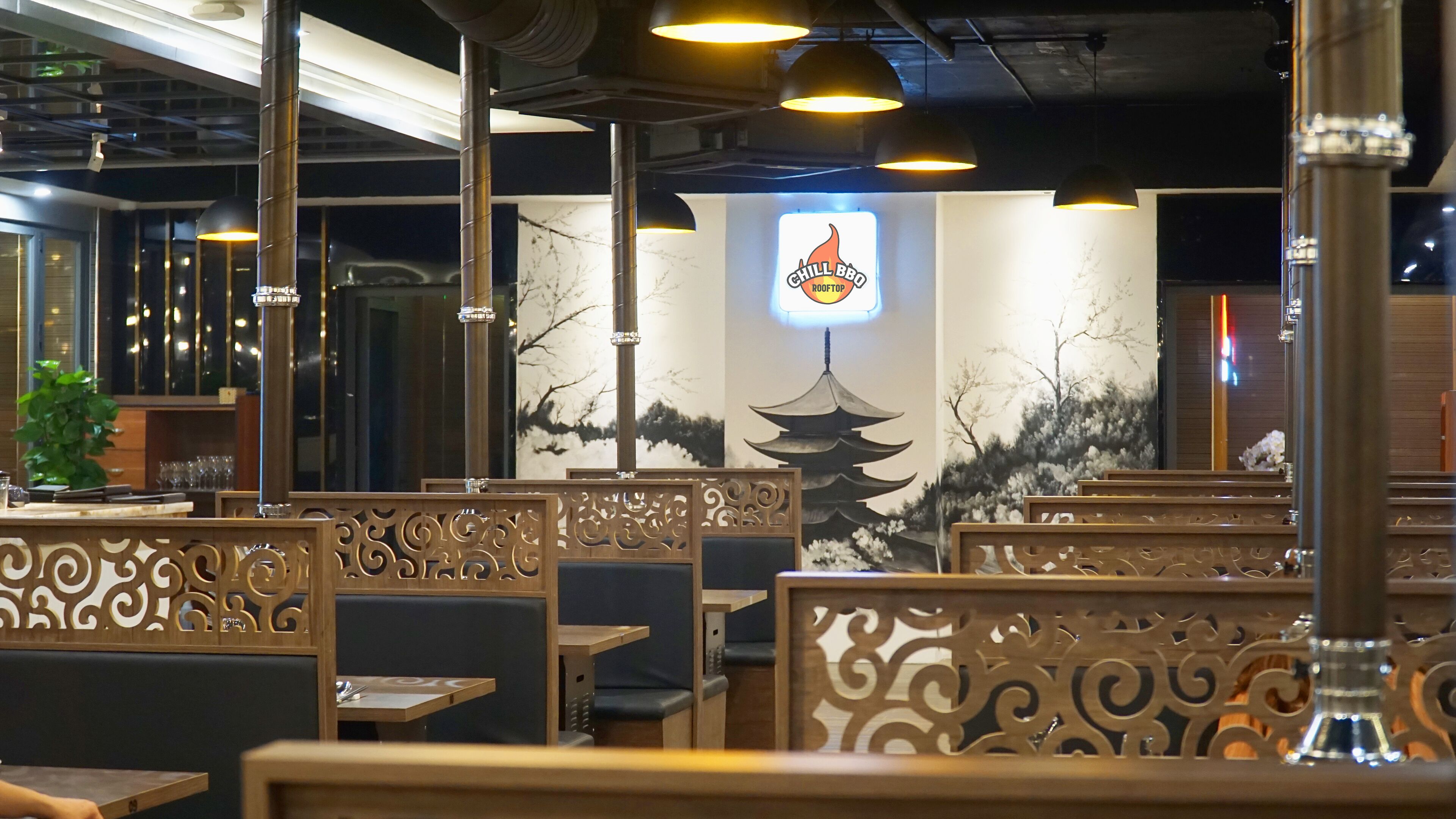 Un interior de restaurante con asientos tipo cabina, decoración en las paredes e iluminación colgante.