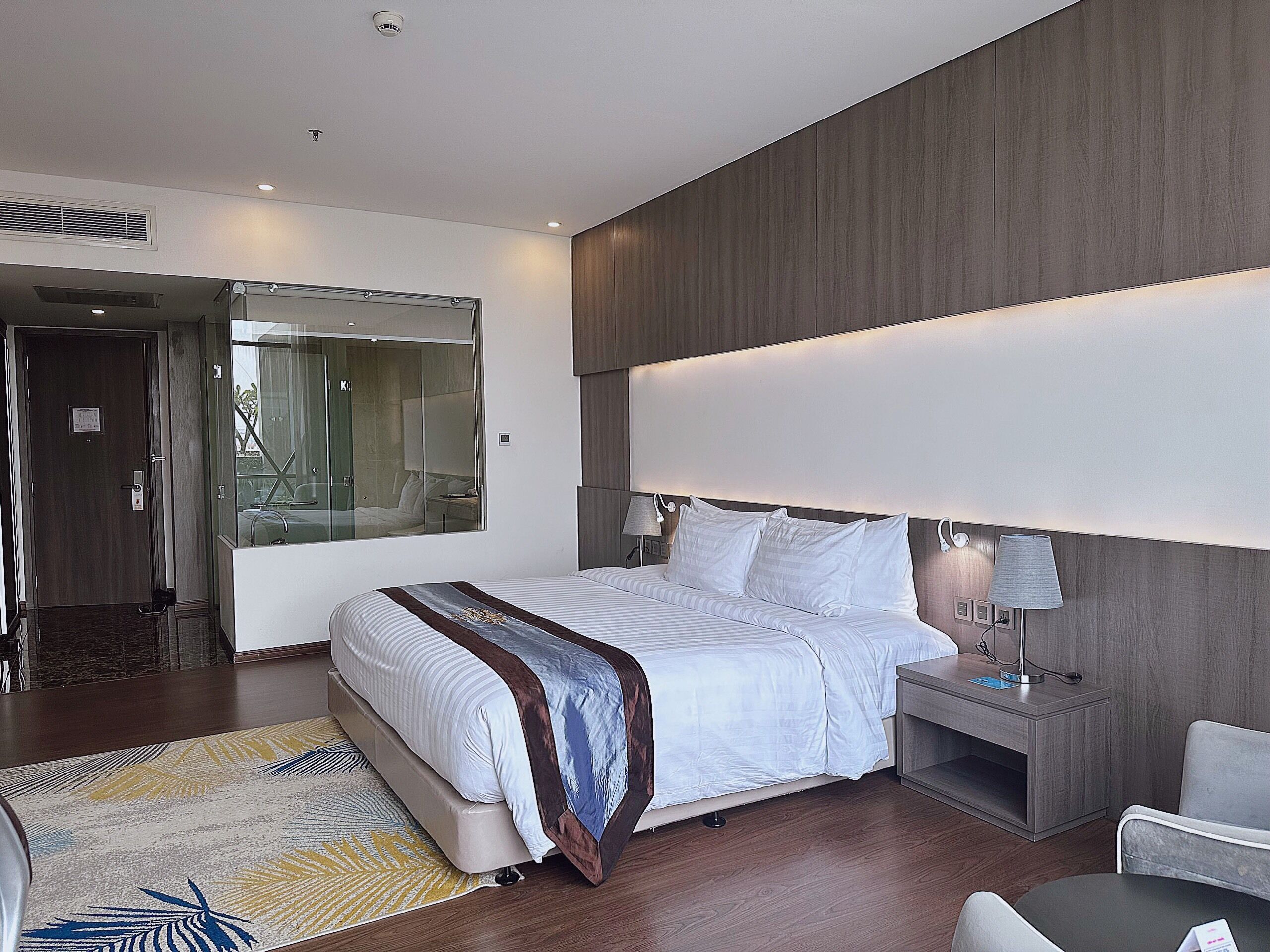 Een moderne hotelkamer met een groot bed, nachtkastjes, een bureau en een stoel.