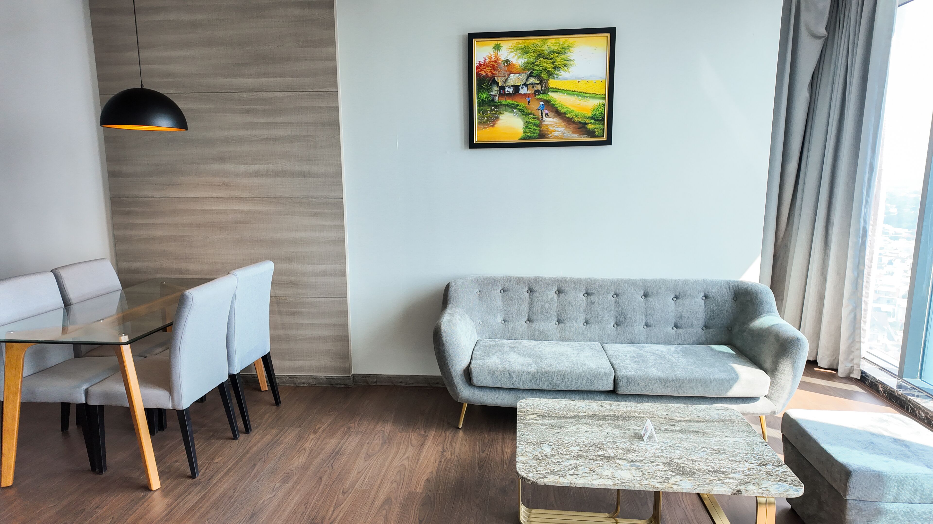 Ein modernes Wohnzimmer mit einem grauen Sofa, einem Glastisch und einem kleinen Couchtisch.