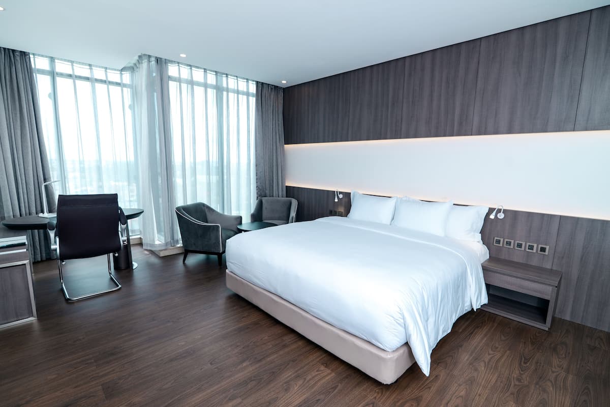 A modern hotel room with a large bed, a desk, and two chairs.