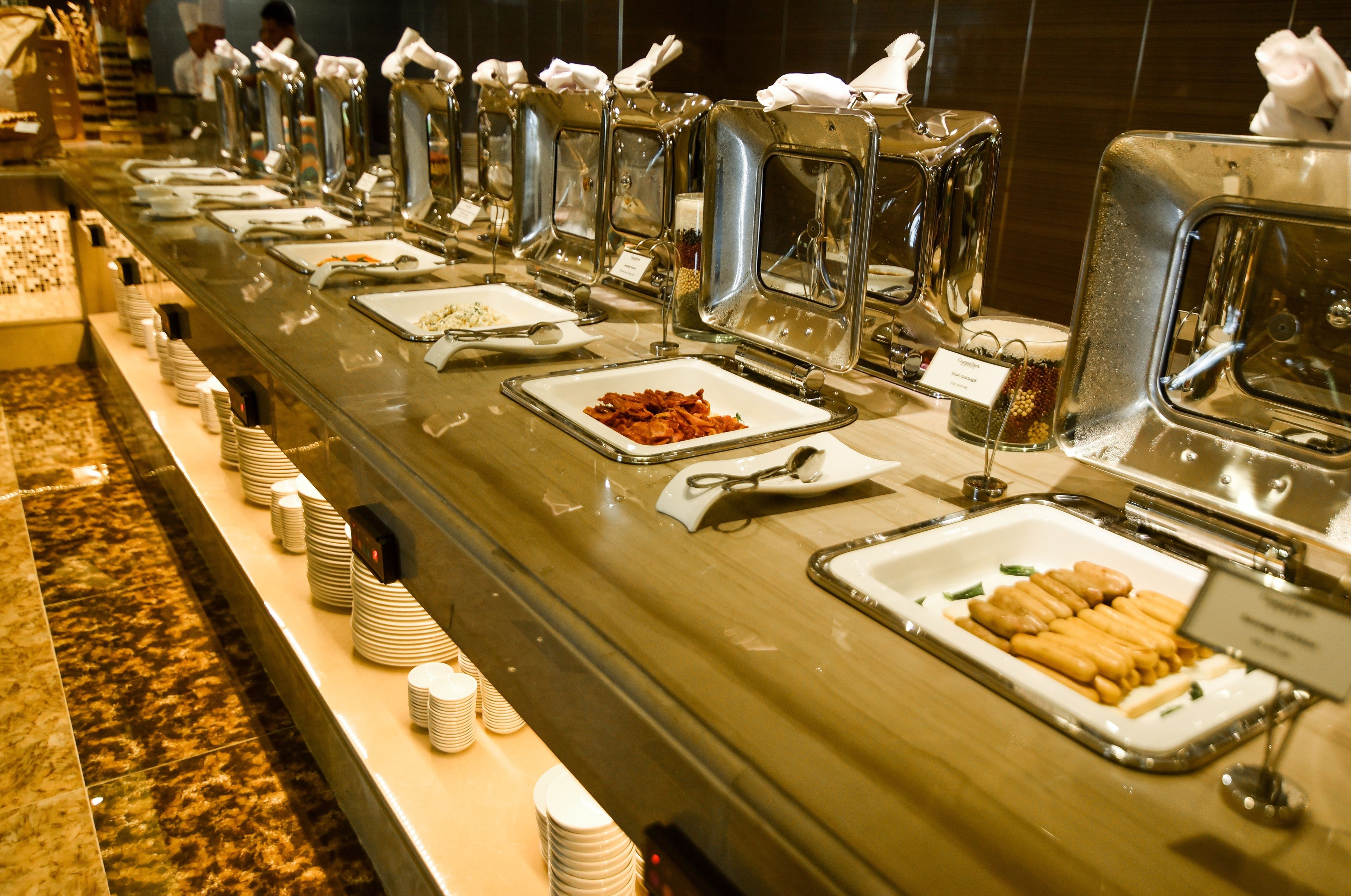 A buffet line with various food items and utensils.