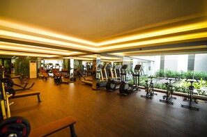 A gym with various exercise equipment, large windows, and a wooden floor. - The Mira Central Park Hotel (Bien Hoa)