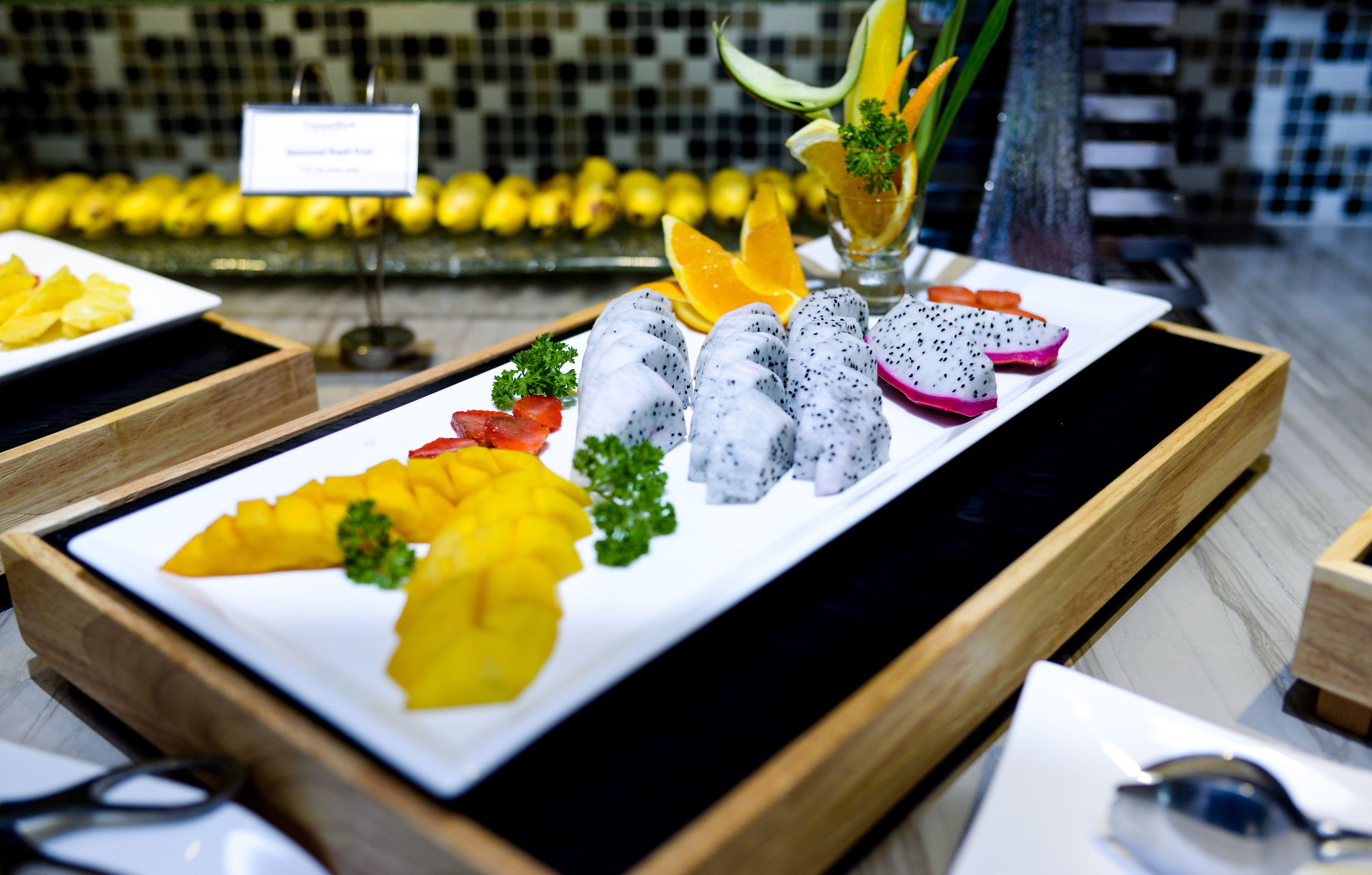 A fruit platter with various fruits and a glass of juice.