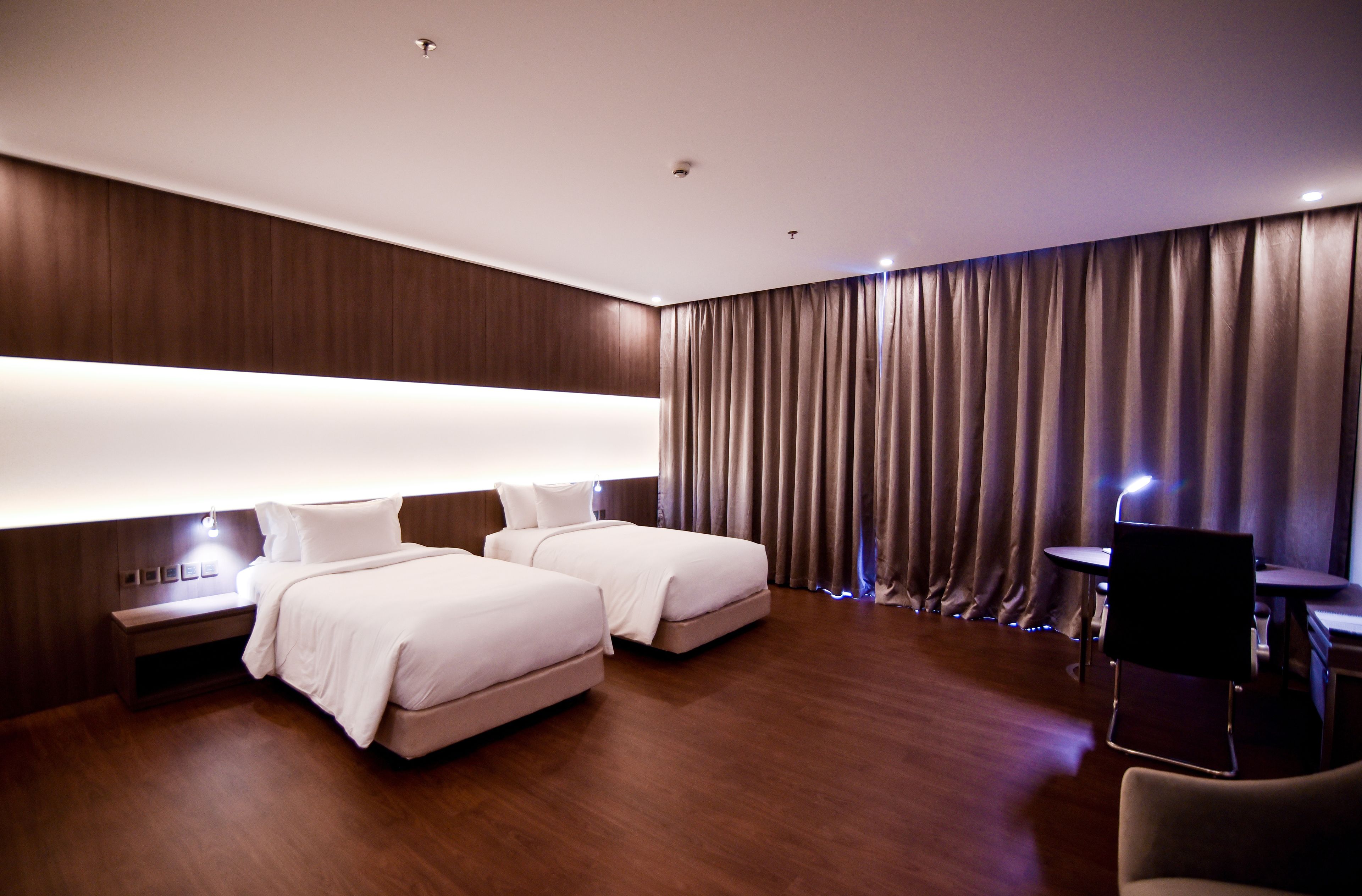 Una habitación de hotel moderna con dos camas, un escritorio y una silla.