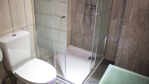 Et badeværelse med toilet, brusekabine i glas og et badekar.