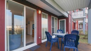 A covered outdoor patio with a table and chairs, a sliding glass door, and a view of a building in the background. - 2 bedroom gorgeous apartment in Rechlin (Rechlin)