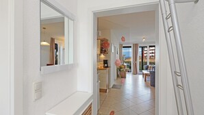 A hallway with a kitchen area, a dining area with a table and chairs, and a view of the sea through large windows. - 2 bedroom gorgeous apartment in Rechlin (Rechlin)