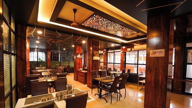 A restaurant with wooden decor, tables, chairs, and a sign indicating ice cream service. - Ramana Towers (Tiruvannamalai)