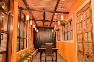 Un restaurante con un largo pasillo, mesas de madera, plantas colgantes y un ventilador de techo.
