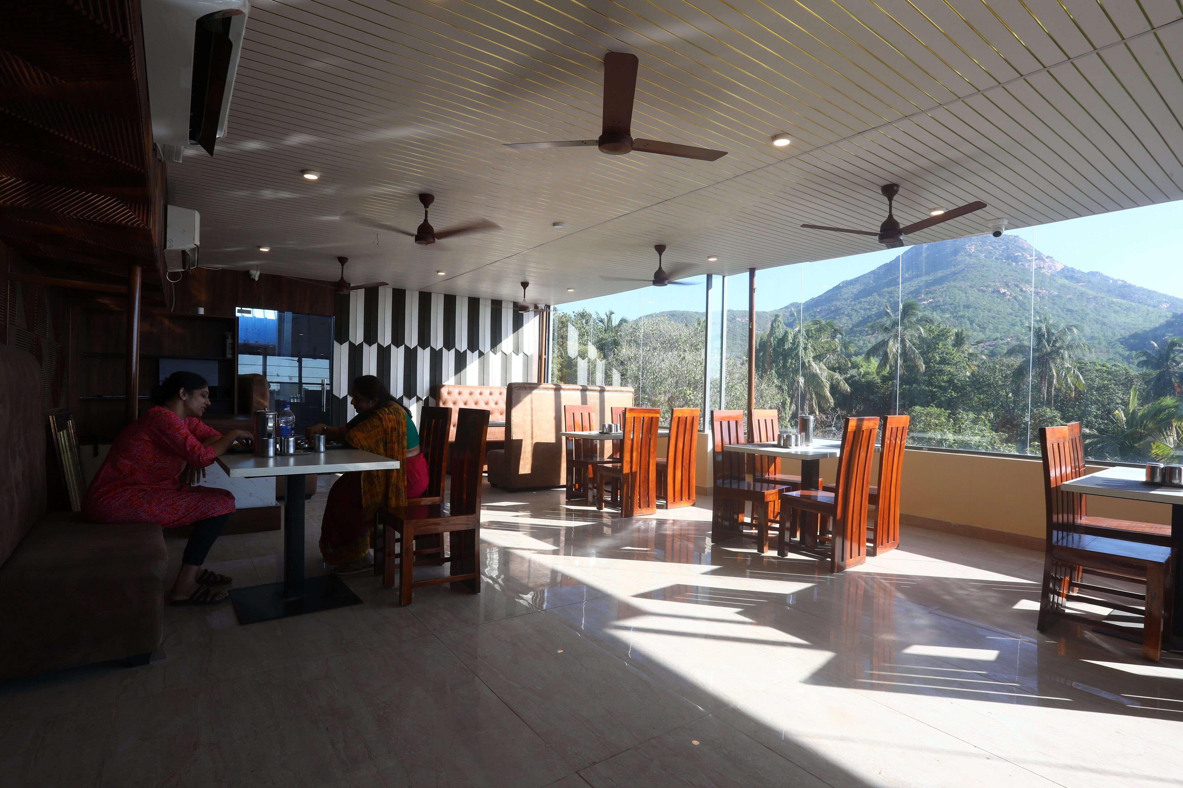 Un restaurante con vistas a la montaña, muebles de madera y ventiladores de techo.