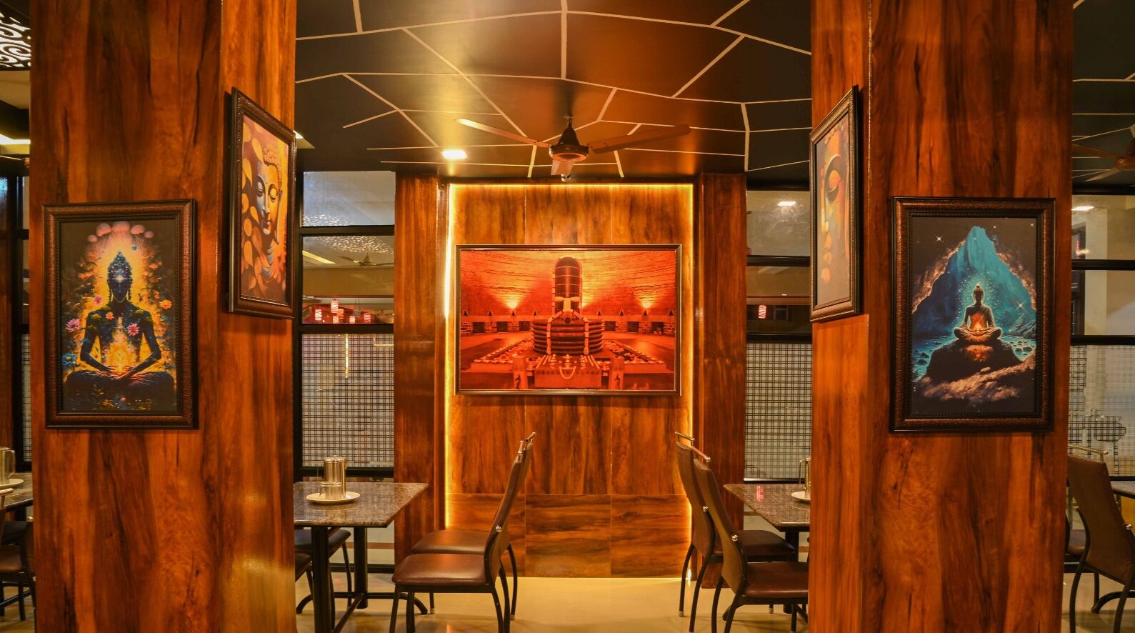 A restaurant interior with wooden paneling, framed artwork, and a central seating area with tables and chairs.