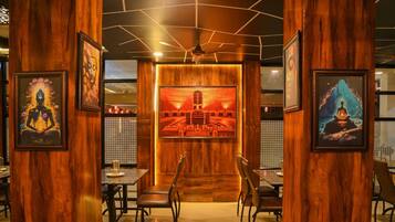 A restaurant interior with wooden paneling, framed artwork, and a central seating area with tables and chairs.