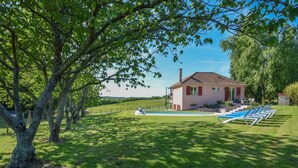Une maison avec une piscine, entourée d’une végétation luxuriante et d’arbres.
