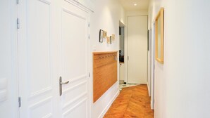 A hallway with white doors, a wooden panel wall, and a herringbone patterned floor.