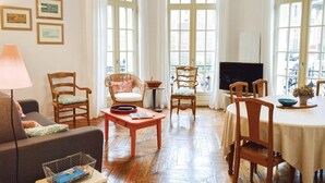 A cozy living room with a sofa, chairs, a table, and a TV.