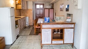 Une cuisine compacte comprenant un réfrigérateur, des placards en bois, une table à manger avec des chaises et un meuble décoratif doté de portes en verre.