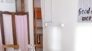 Une table de salle à manger en bois, recouverte d’une nappe blanche, avec une carafe et un plateau de verres à vin.