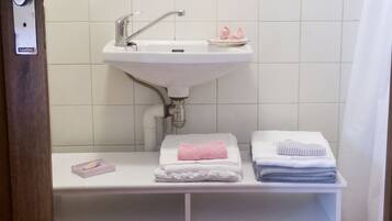 A bathroom with a white sink, a mirror, and a red towel on the floor.