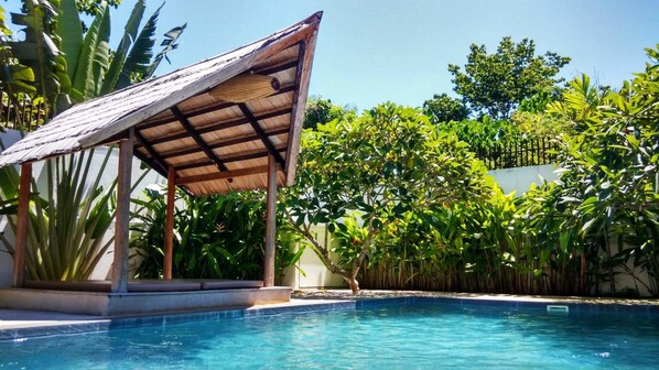 Una piscina al aire libre, sillones reclinables de piscina