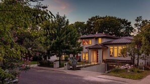 A modern two-story house with a metal roof, a front porch, and a driveway.