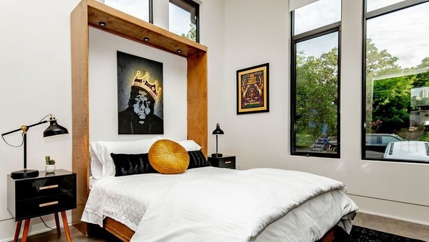 A bedroom with a bed, a nightstand, a lamp, and two framed pictures on the wall.