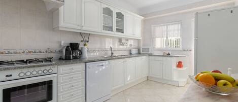 A modern kitchen with white cabinetry, a gas stove, a dishwasher, and a fruit bowl on the counter.